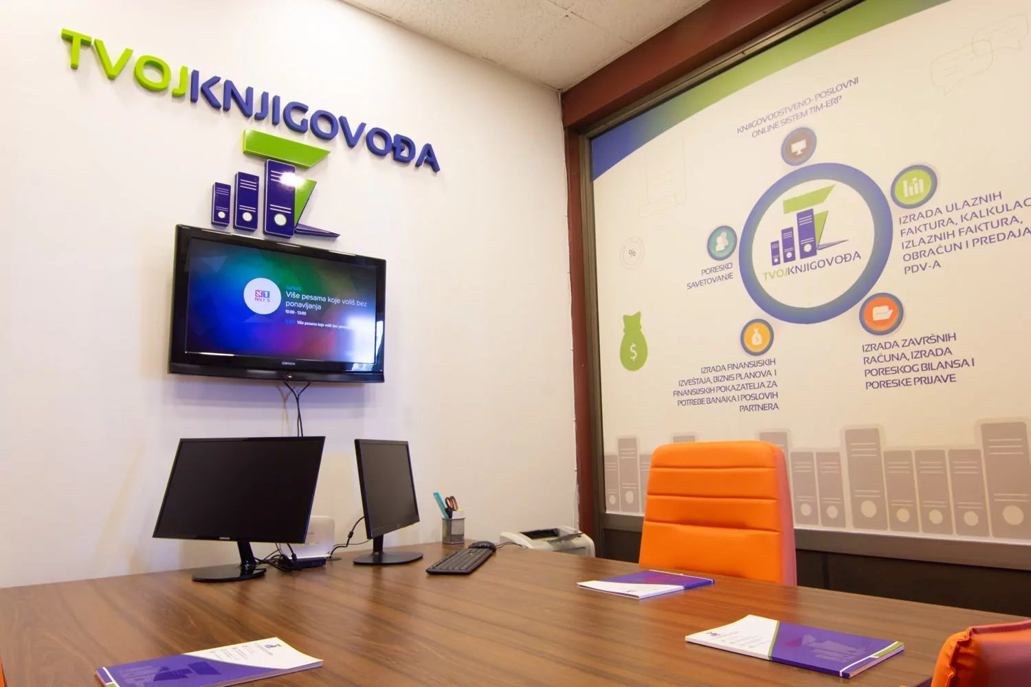 Sala za sastanke — sto sa materijalom za klijente i logo na zidu